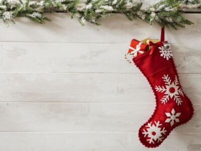 red stocking filled with small gift, garland above, on white background