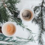 warm drinks in mugs surrounded by evergreen branches