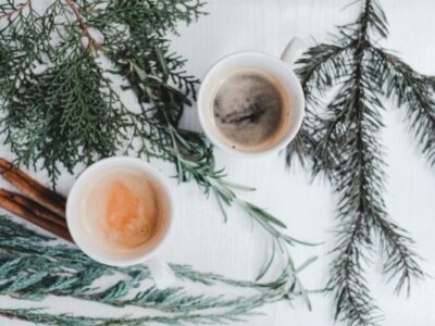 warm drinks in mugs surrounded by evergreen branches