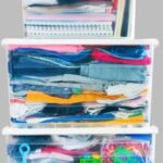 organizing products that are clear storage bins filled with clothes notebooks toys on gray background
