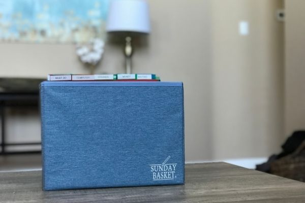 The Sunday Basket System - blue. On wooden table with lamp in background.