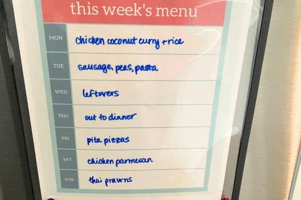 meal plan posted on stainless steel fridge. says "this week's menu" and then lists out all of the meals for the week in blue handwriting