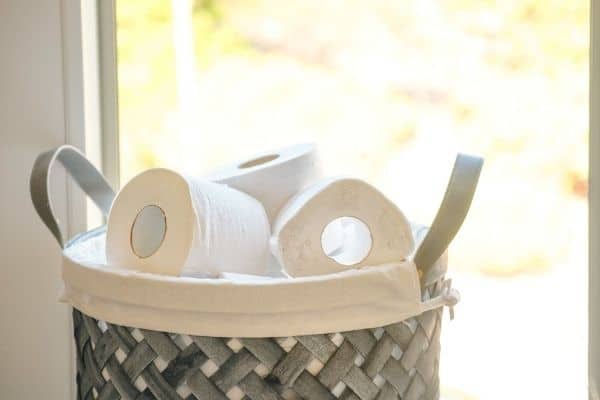 gray basket filled with toilet paper rolls