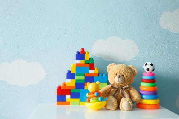 A teddy bear sitting on a table surrounded by toys