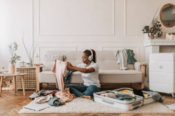 Woman who knows how to travel organized packing suitcase while listening to headphones