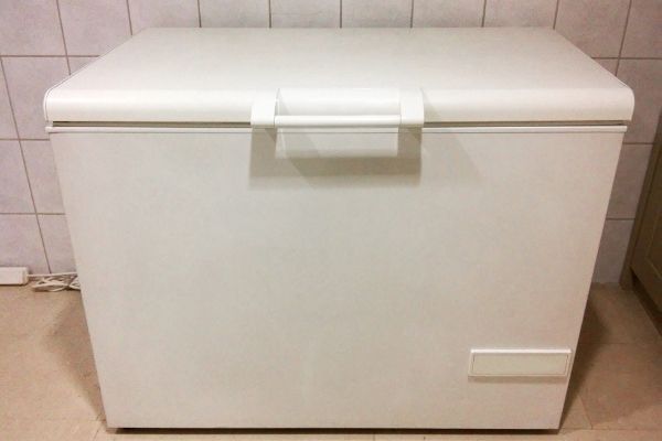 white deep freezer in front of wall with white tile