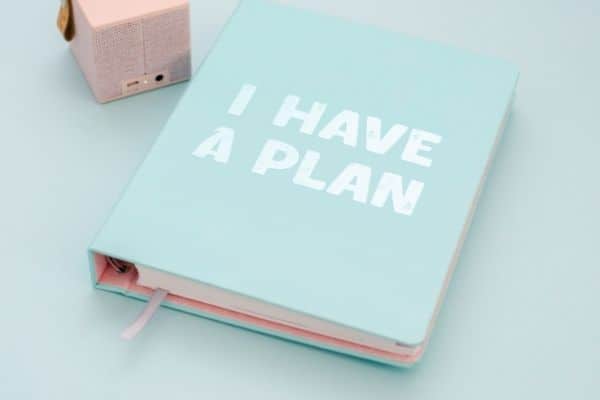 mint colored planner that says i have a plan on a white table