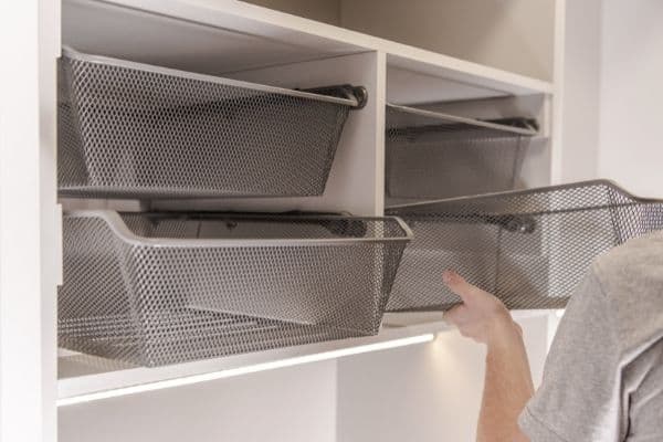 wire baskets on rails in storage space, woman putting basket away