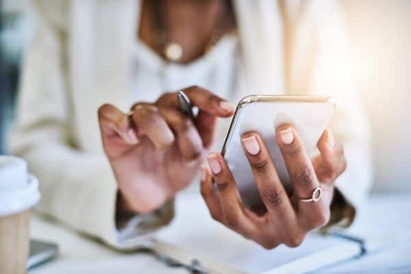 woman wearing white suit entering appointment into her cell phone