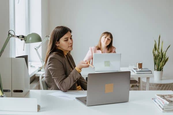 two women working in an office together using laptops