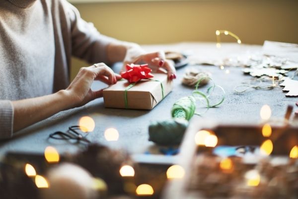 wrapping christmas presents surrounded by twinkle lights