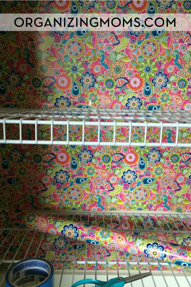 Wrapping paper used as wallpaper in back of linen closet, wire shelf in foreground.